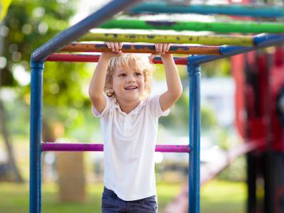 A child smiles while playing on monkey bars